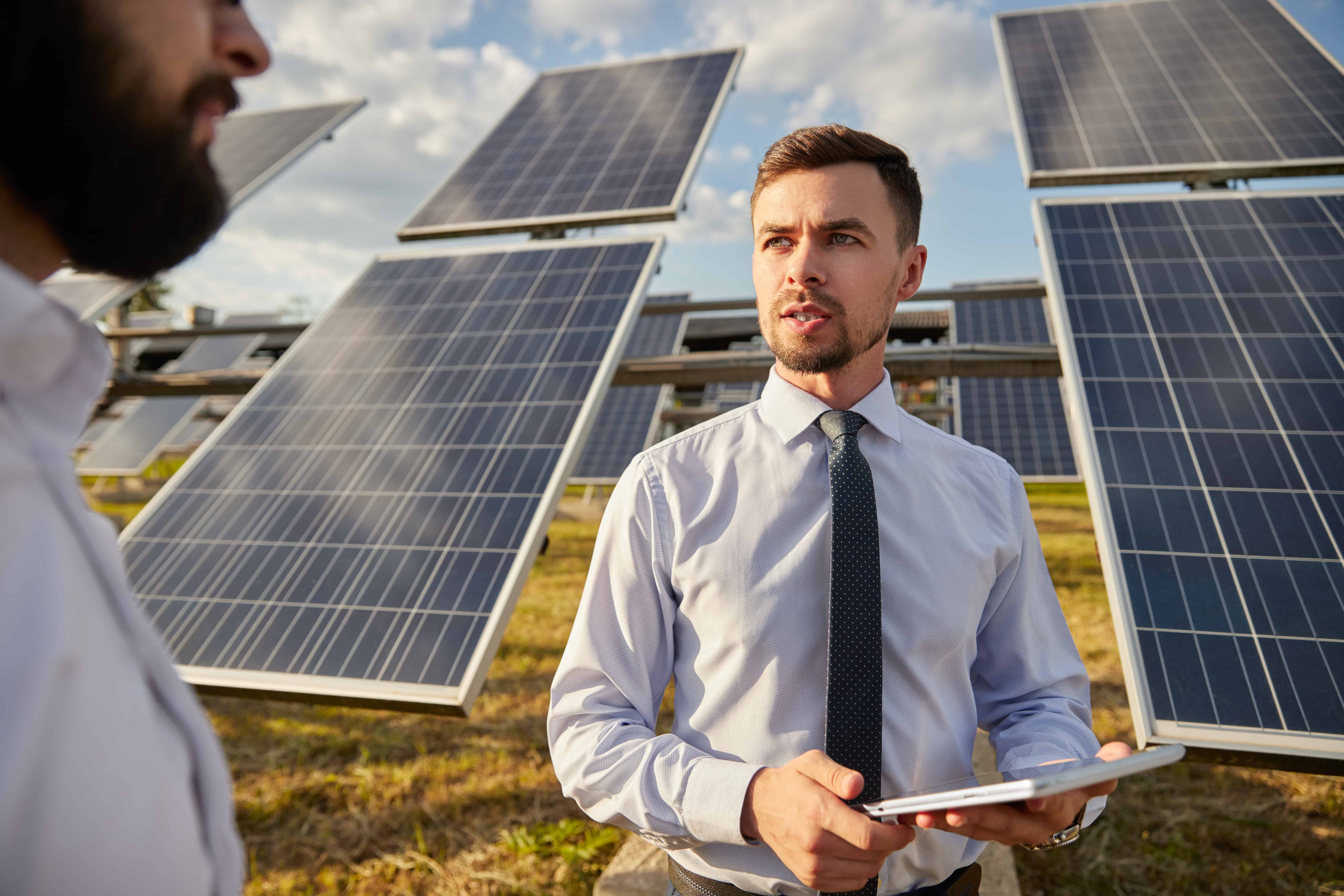 Two men at solar panels on sunny day